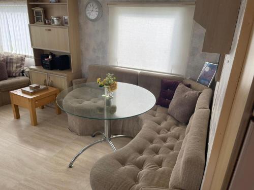 a living room with a couch and a glass table at Lake District Caravan in Cockermouth