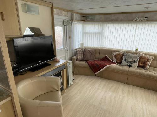 a living room with a couch and a flat screen tv at Lake District Caravan in Cockermouth