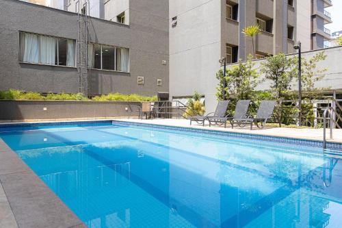 a large blue swimming pool with chairs and a building at Elegant Flat Paulista Alameda Campinas Garagem , Pool, Ar Cod, in Sao Paulo