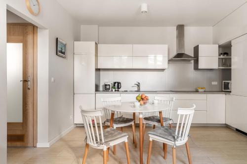 - une cuisine blanche avec une table et des chaises dans l'établissement Sanhaus Apartments - Apartament LIDO - 300 m od plaży, à Sopot
