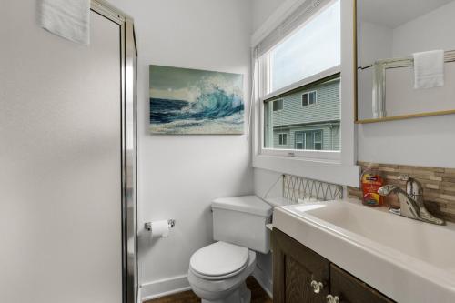 a bathroom with a toilet and a sink and a window at The Tides by the Sea in Seaside
