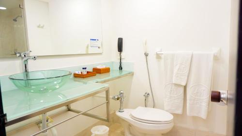 ein Badezimmer mit einem Glaswaschbecken und einem WC in der Unterkunft Hotel Tonchalá in Cúcuta
