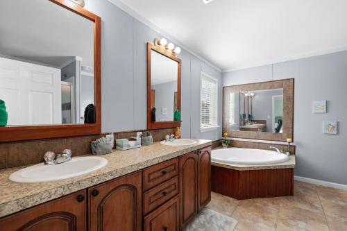 a bathroom with two sinks and two mirrors at Villa Island Retreat, Country house overlooking 13 acres and a small lake in Saint James City