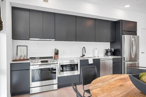 a kitchen with stainless steel appliances and a wooden table at Penthouse River View Walk Downtown, Garage Parking in Nashville