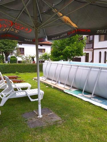 a row of white lounge chairs under an umbrella at Vila Omainiche Ribarica in Ribarica