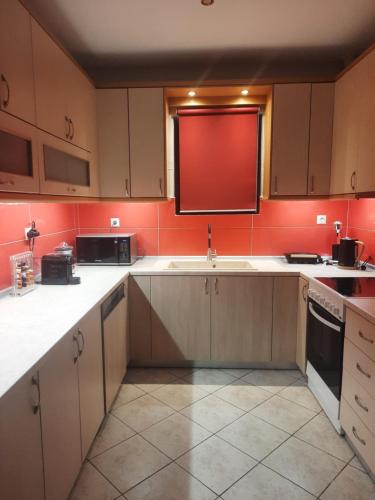 a kitchen with white cabinets and a red wall at Marathon VS LUXURY VILLA in Grammatiko