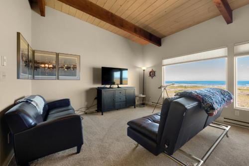 a living room with two chairs and a couch and a television at The Tides by the Sea in Seaside