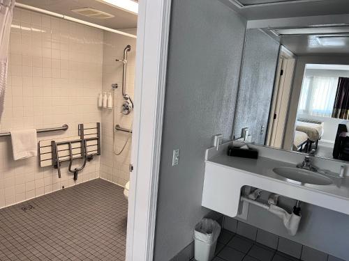 a bathroom with a sink and a shower and a mirror at Travelodge by Wyndham Redding CA in Redding