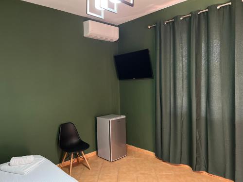 ティラナにあるTirana Roomsの緑の壁のベッドルーム(椅子、テレビ付)