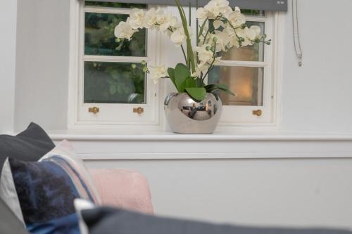 a vase with white flowers sitting on a window sill at Historical Holmehill Lodge in Dunblane