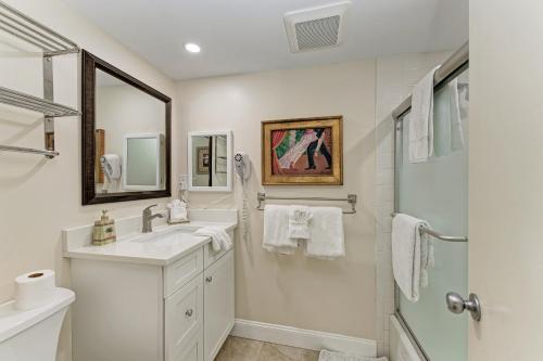 uma casa de banho branca com um lavatório e um chuveiro em Sea Grape Inn 4- BEACHFRONT Property em Longboat Key