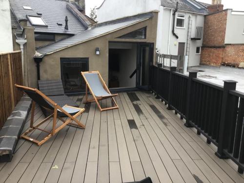 a pair of chairs sitting on a deck at The Curious Apartment, Cheltenham in Cheltenham