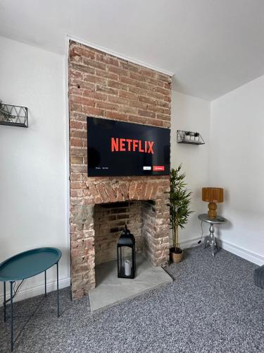 a living room with a fireplace with a television on a brick wall at Waterloo Street in King's Lynn