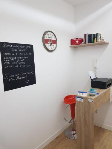 a chalkboard on a wall with a desk and a clock at B&B Gisa House in Pomigliano dʼArco