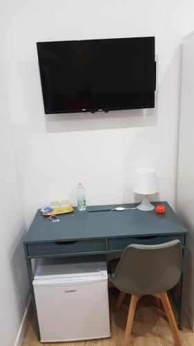 a blue desk with a television on a wall at B&B Gisa House in Pomigliano dʼArco