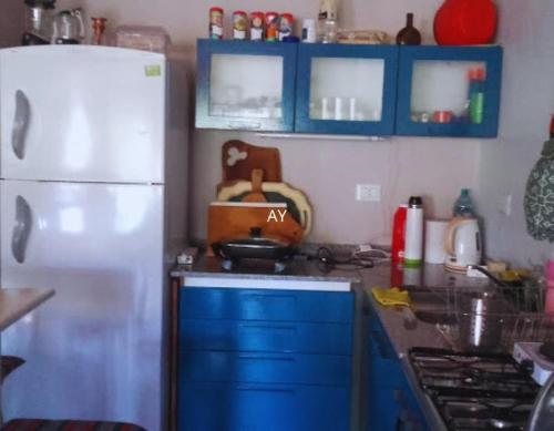 a kitchen with blue cabinets and a white refrigerator at CABAÑA MI PAZZ camino al cuadrado in Cordoba