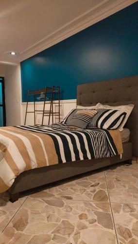 een slaapkamer met een bed met een blauwe muur bij Loft privado San Jerónimo in León
