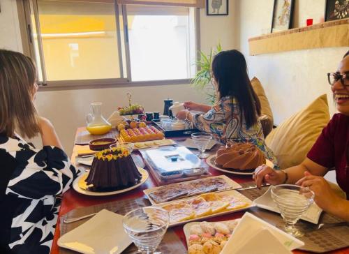 a group of people sitting around a table with cakes at Maison D'hôtes Des Belges in Dakhla