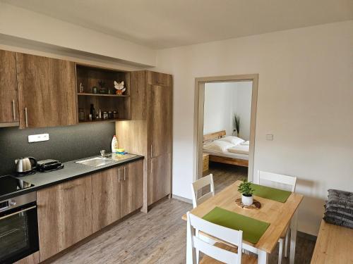 a kitchen and dining room with a table and a room with a bed at Apartmány Karolína - Kašperské Hory in Kašperské Hory