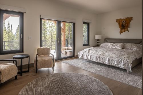a bedroom with a bed and a chair and windows at Skylark Chalet in Big Sky