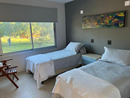 1 dormitorio con 2 camas individuales y ventana en La casa de la villa belgrano en Villa General Belgrano