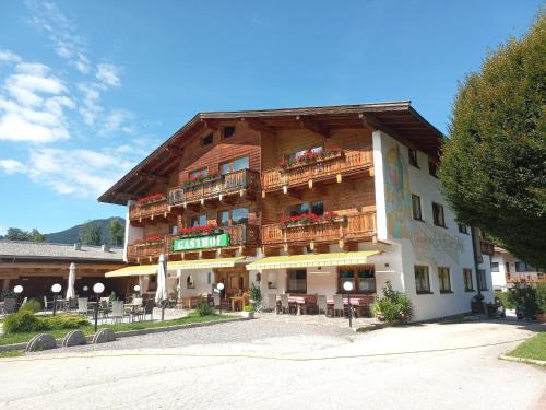 un gran edificio con mesas y sillas delante de él en Scheffauerhof, en Scheffau am Wilden Kaiser