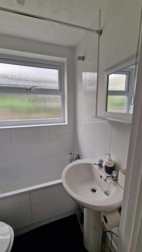 a white bathroom with a sink and a bath tub at Saxon Street House in Gillingham