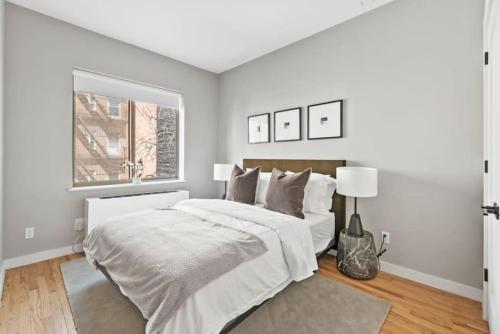 a white bedroom with a large bed and a window at Top Notch 2BR Suite Minutes to Central Park in New York
