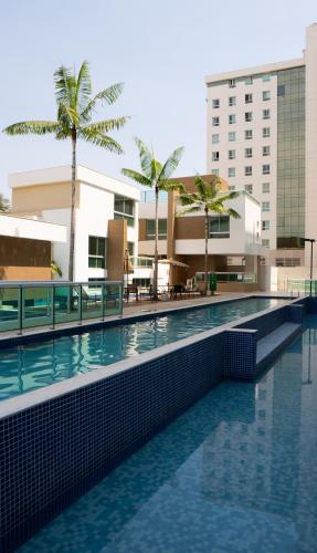 a swimming pool in front of a building with palm trees at Jade Hotel Brasília in Brasilia