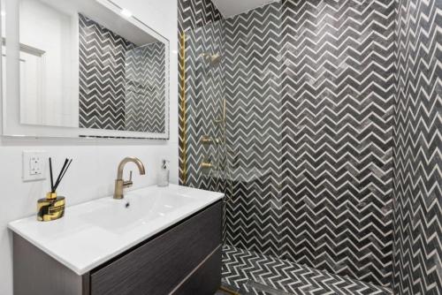 a bathroom with a sink and a checkered wall at Top Notch 2BR Suite Minutes to Central Park in New York