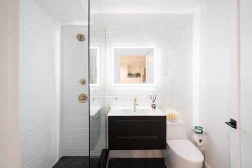 a white bathroom with a sink and a toilet at Luxury 2BR Duplex 5min to Central Park in New York