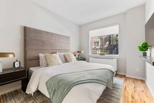 a bedroom with a large bed and a window at Luxury 3BR Duplex w Private Patio in Upper East in New York