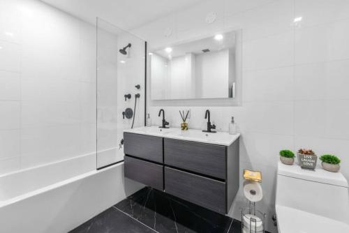 a white bathroom with a sink and a mirror at 3BR Penthouse Suite with Massive Private Rooftop in New York