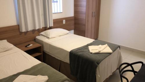 a hotel room with two beds and a table and chairs at Hotel Oitis in Governador Valadares