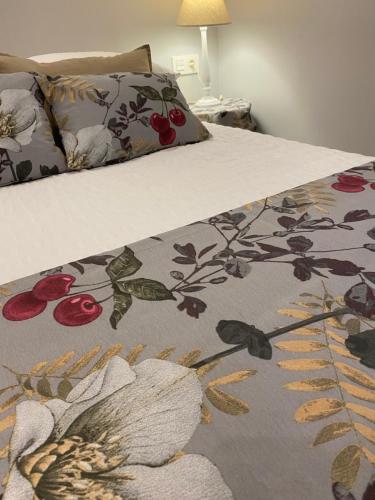 Una cama con una manta con flores. en Precioso y céntrico apartamento, en Zaragoza