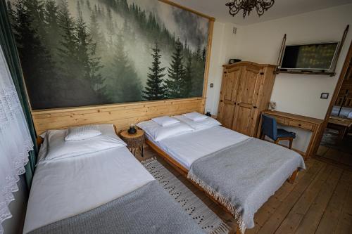 two beds in a room with a large painting on the wall at Zacisze Pod Reglami in Zakopane