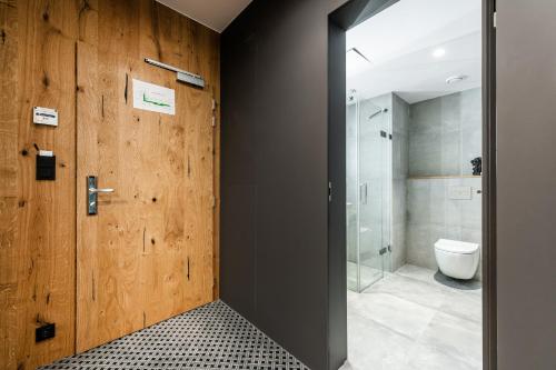 a bathroom with a wooden door and a toilet at Rezidence Alpina in Špindlerův Mlýn