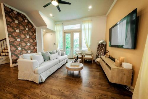 a living room with a white couch and a tv at Downtown Escape - Backyard, Game room and Free Parking in Houston