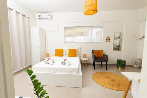 a white bedroom with a bed and a chair at Studio Apartment Volterra Curacao in Willemstad