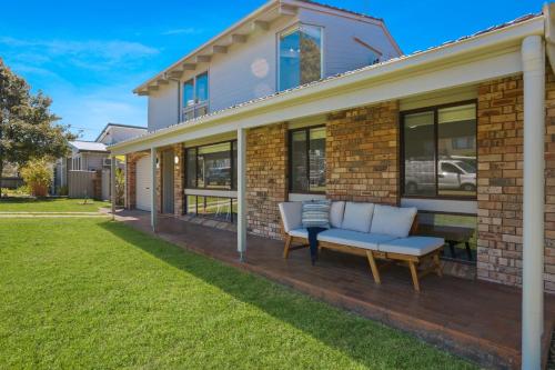 a brick house with a bench on the front yard at Sunrise Point Beach House by Experience Jervis Bay in Vincentia