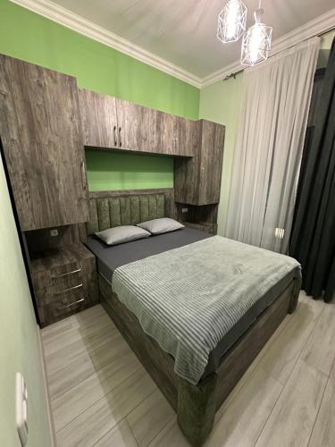 Schlafzimmer mit einem großen Bett mit einem Kopfteil aus Holz in der Unterkunft Comfy Apartment in Center in Yerevan
