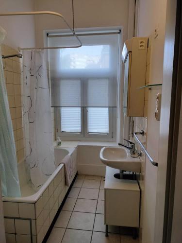 ein Bad mit einer Badewanne, einem Waschbecken und einem Fenster in der Unterkunft City Home Zurich in Zürich