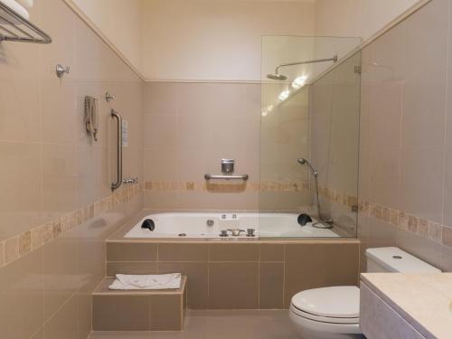 a bathroom with a tub and a toilet and a sink at LP Los Portales Hotel Piura in Piura