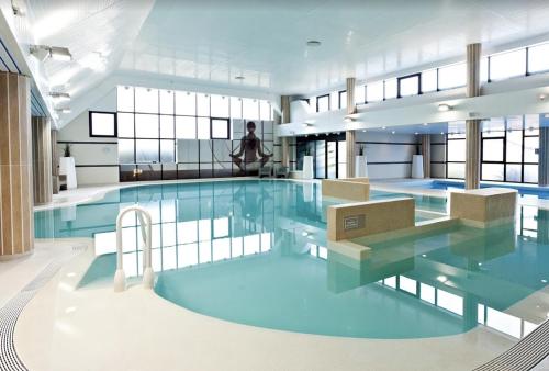 une grande piscine avec de l'eau bleue dans un immeuble dans l'établissement Arlette, à Ouistreham