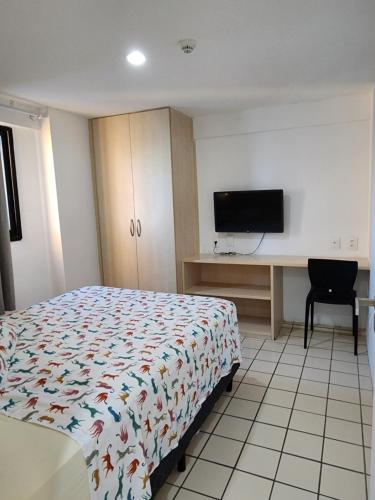 um quarto com uma cama e uma secretária com uma televisão em Flat em Boa Viagem - perto da praia no Recife