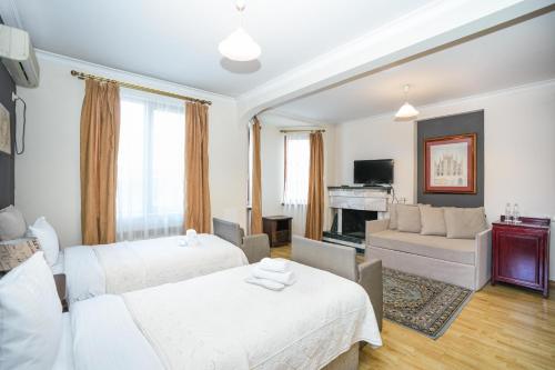 a bedroom with two beds and a living room at Beaumonde Hotel Tbilisi in Tbilisi City