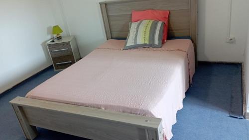 Dormitorio pequeño con cama con sábanas rosas y mesita de noche en Maison du soleil, en Les Abymes