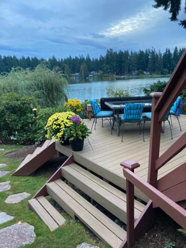 a wooden deck with chairs and a table on a lake at Cottage Lake Bed and Breakfast in Woodinville