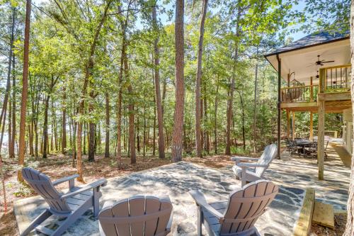 a patio with chairs and a deck in the woods at Luxury Lakefront Retreat with Deck and Patio! in Fairfield Bay