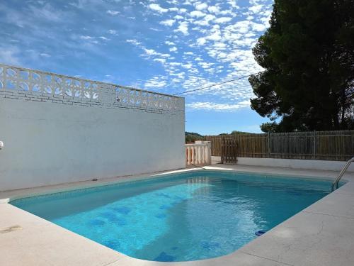 une piscine d'eau bleue en face d'une clôture dans l'établissement Large yard, large lawn, independent villa, à Llíria